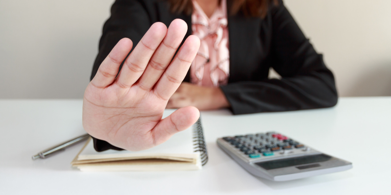 Woman in business attire holding out her hand in a preventive pose Woman in business attire holding out her hand in a preventive pose