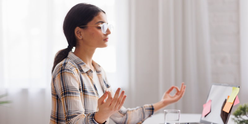 Woman in a meditative pose in front of a laptop Woman in a meditative pose in front of a laptop