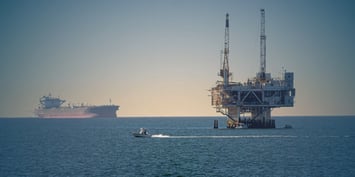 An offshore drilling platform with an FLNG facility in the background