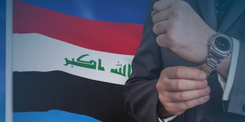 A professional in a suit adjusts their wristwatch against the backdrop of the Iraqi flag, reflecting the opportunities for companies hiring employees in Iraq.