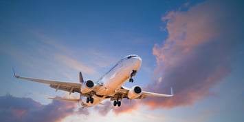 An aircraft in flight against a vibrant sky filled with clouds, illustrating the concept of travel and job opportunities.