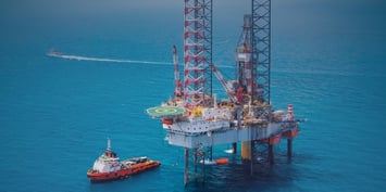 An oil rig stands prominently in the ocean, surrounded by water, showcasing its structure and equipment for drilling operations.