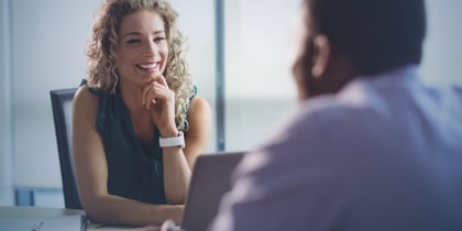 A curly haired woman smiles at a potential employee during an interview 