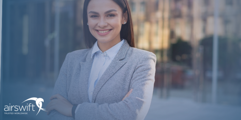 A woman stands outside an office building wearing a smart grey suit