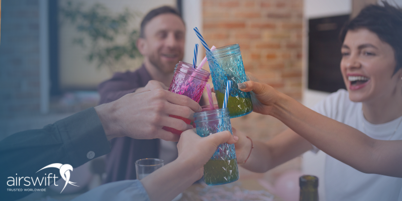  Happy colleagues make a toast in the office with colourful drinking glasses