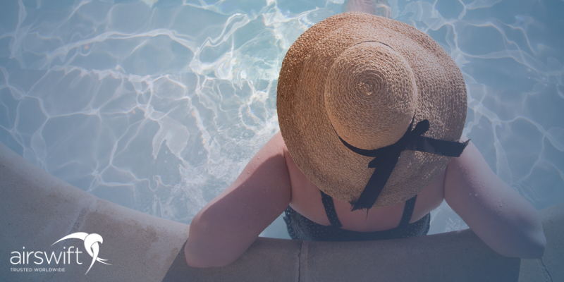 A woman relaxes in a swimming pool, she is wearing a sun-hat 