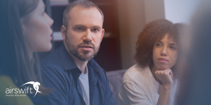 A man listens to two of his team members, the discussion looks thoughtful and engaging