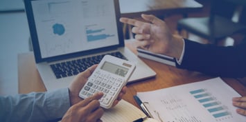 Coworkers discuss the budget of a project and evaluate the costs. One of them has a calculator in his hands.