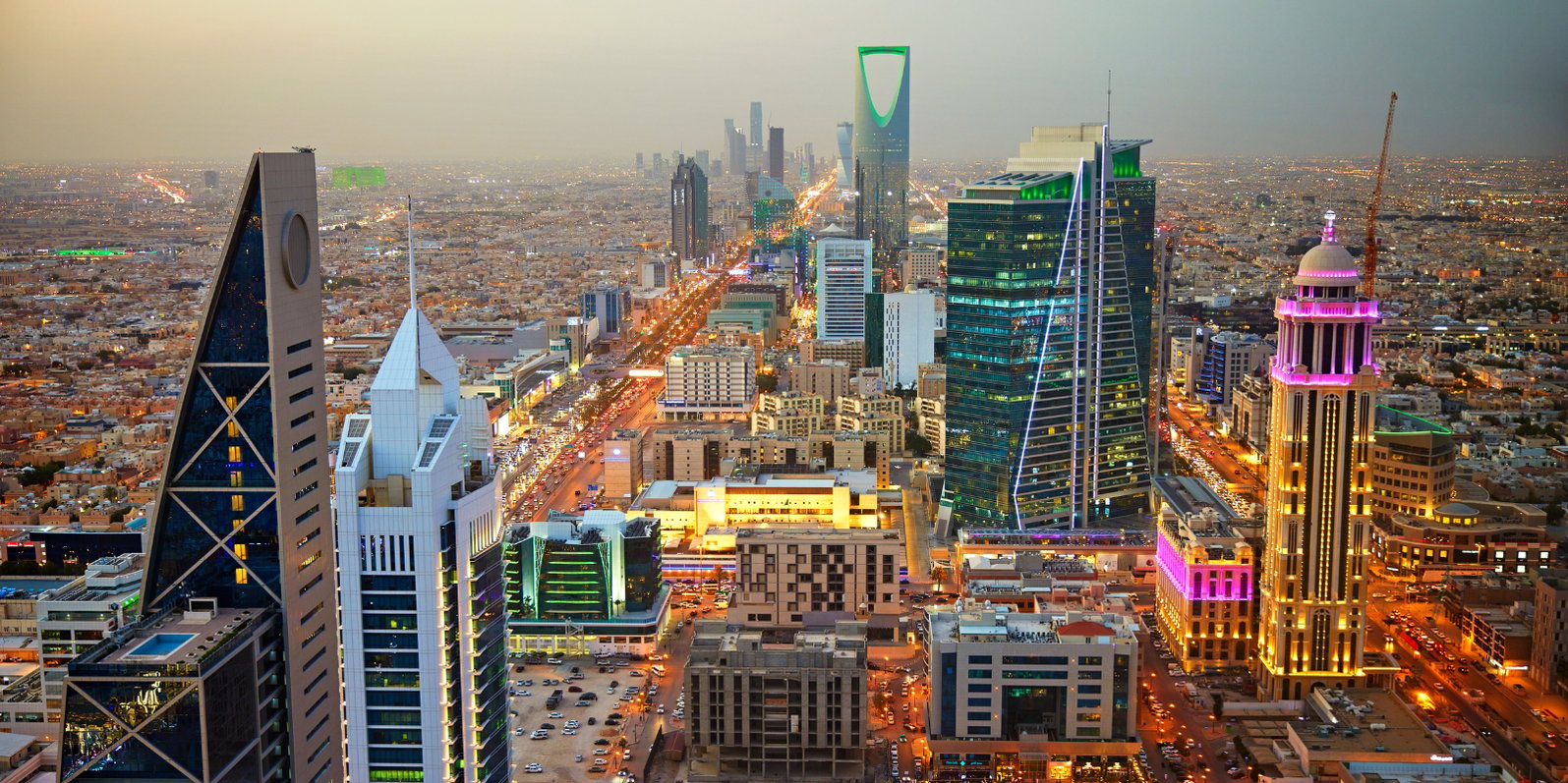 A high up shot of the Saudi Arabian skyline with high rise buildings and lights from cars and buildings