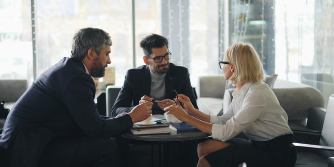 Three business people sitting at a table talking