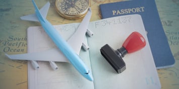 Travel documents and passport with airplane model and visa stamp illustrating the process of getting a work visa or work permit in Canada for international workers.