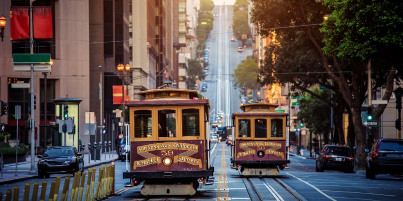 historic traditional Cable Cars riding on famous California Street in morning light in San Francisco,