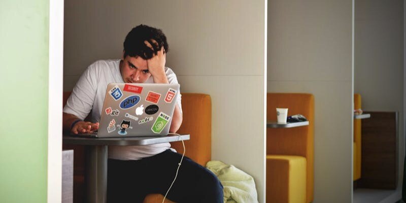 man sat in a booth, concentrating on a laptop