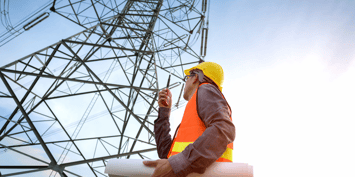  Engineer with hardhat and plans under electricity pylon representing power employment trends