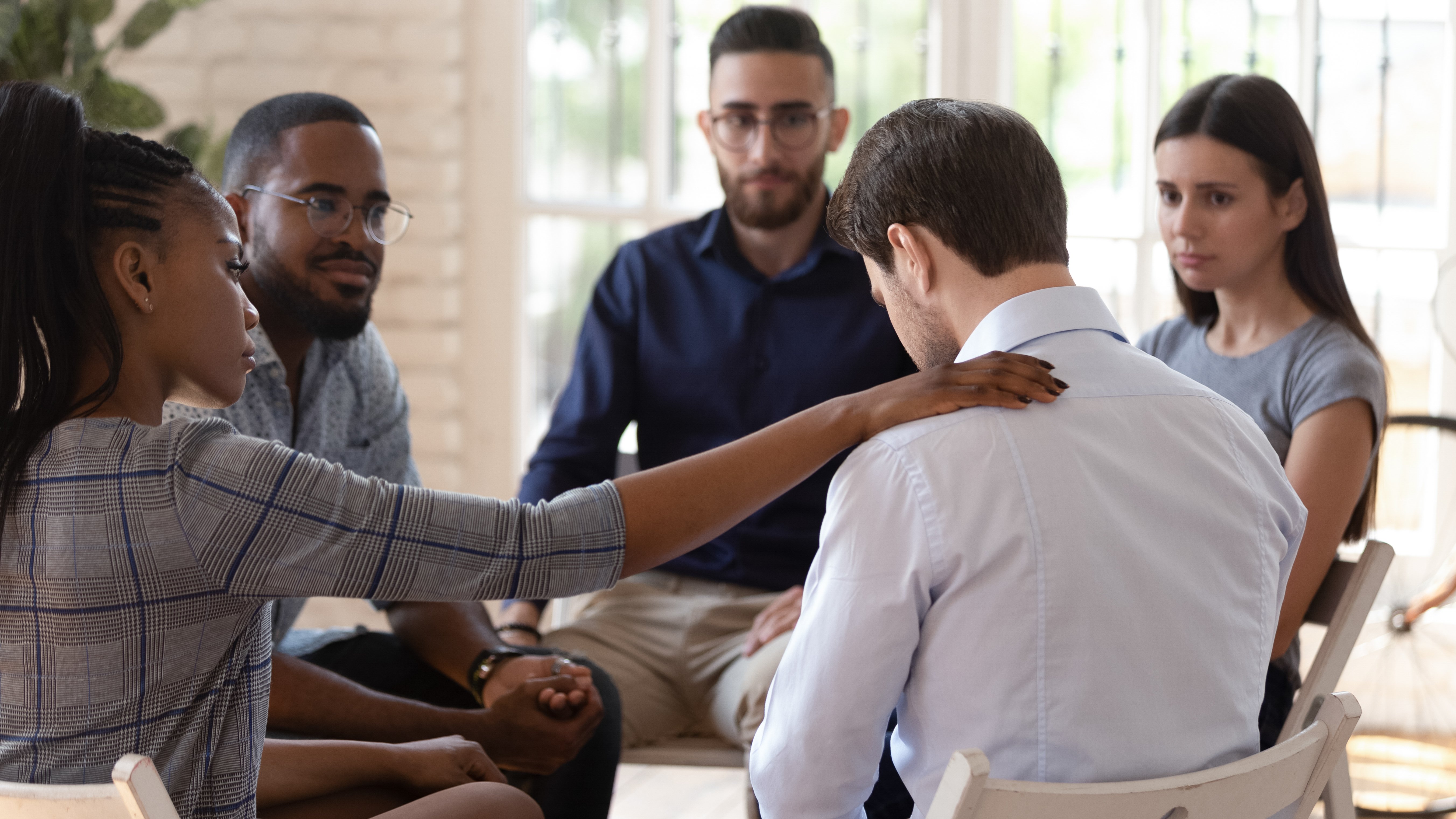 Rear view at upset man getting psychological support of colleagues