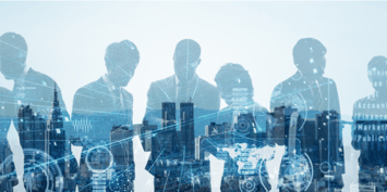 Several people in business attire having a business discussion reflected on a window, with the backdrop of an urban skyline.