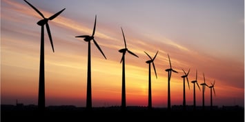 Row of wind turbines silhouetted against a vibrant sunset sky, symbolising large-scale wind energy generation in the United States. This image represents major U.S. wind energy projects scheduled to start in 2026 and beyond.