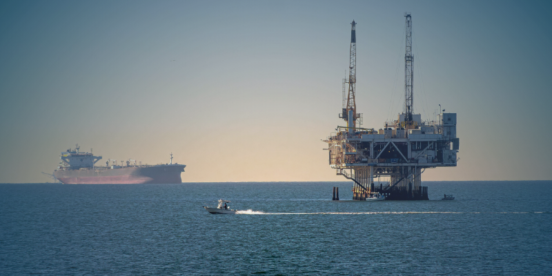 An offshore drilling platform with an FLNG facility in the background