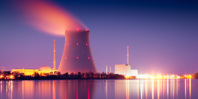 Nuclear power plant at twilight with illuminated cooling tower