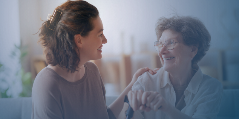 young and elderly woman sitting on couch and smiling at each other